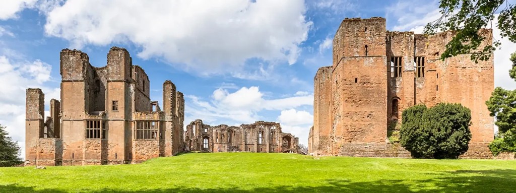 Kenilworth Castle ruins on a green lawn under a blue sky