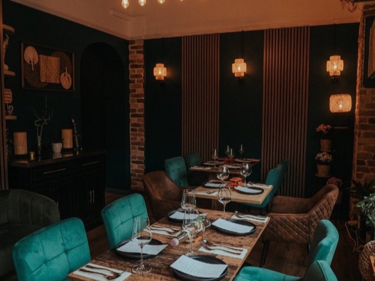 Stylish interior of Piraso restaurant with rustic wooden tables, teal chairs, and warm industrial lighting