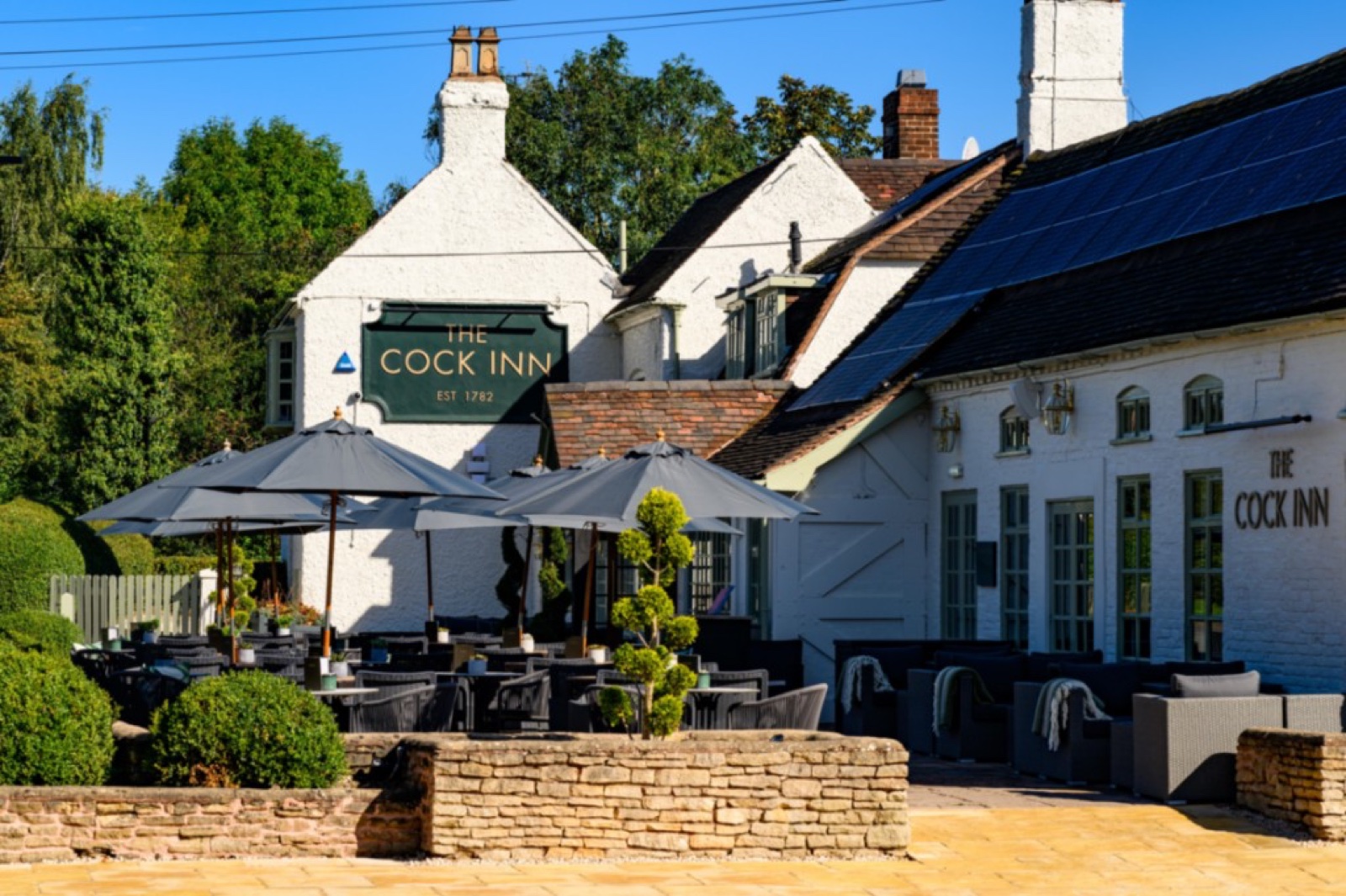 The Cock Inn pub exterior with patio seating in Wishaw
